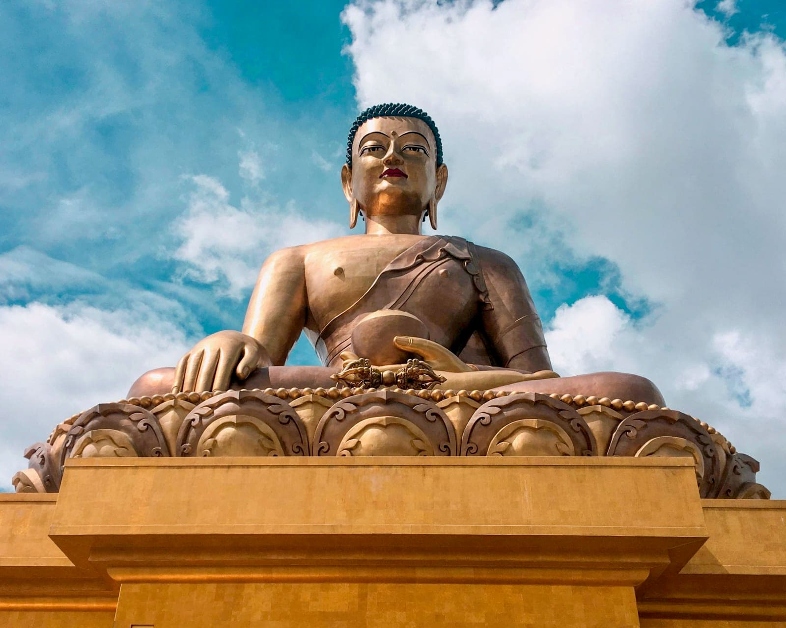 golden buddha statue under a partly cloudy blue sky during day