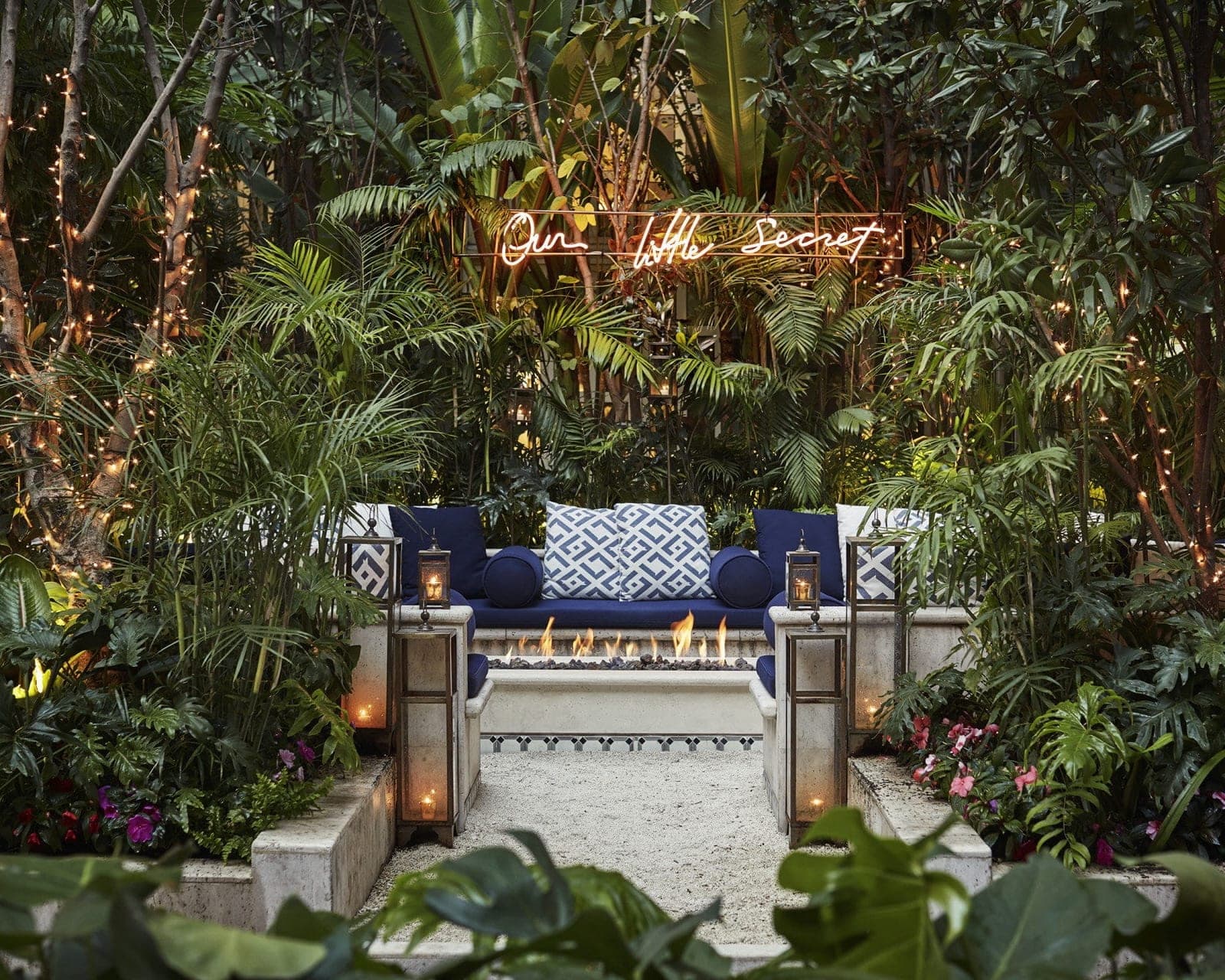 firepit and seating area surrounded by greenery and lights