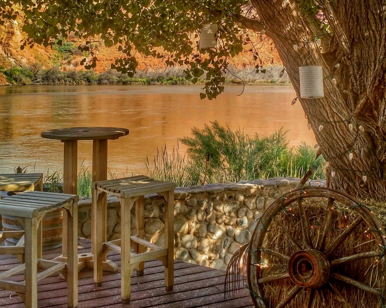 wood deck with stools and table next to a river