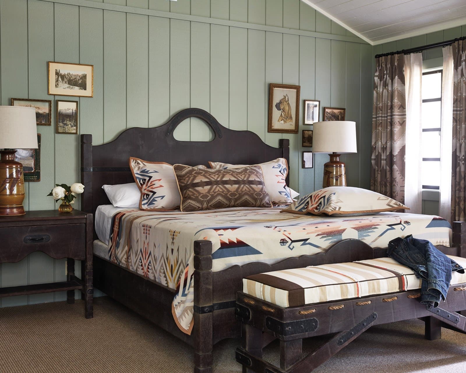 dark wood bed, ottoman and bedside nightstands with light green walls in rustic hotel room