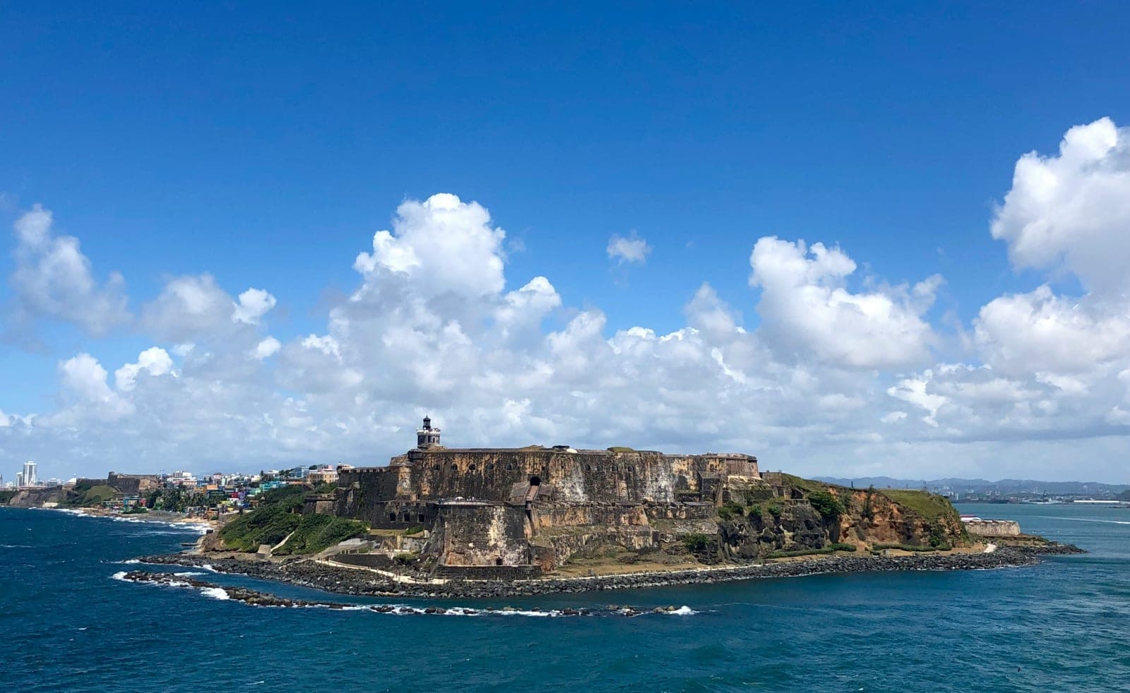 Aerial view of an old colonial fort on a peninsula with blue ocean water and blue skies with clouds at daytime